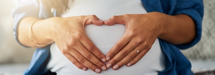 Chiropractic Bakersfield CA Pregnancy Pregnant woman with heart hands over round belly.