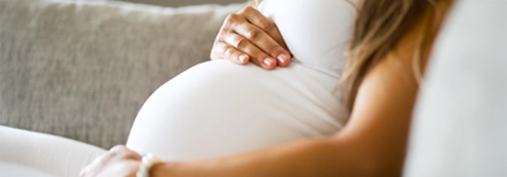 Chiropractic Bakersfield CA Pregnant Woman Pregnant woman holding her belly on a couch.